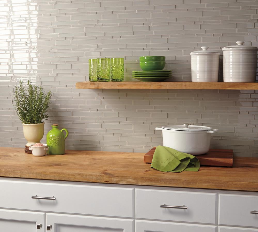 grey random linear mosaic tiles on kitchen backsplash behind butcher block counter with green accent plates