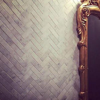 Elegant gold mirror pops against dark Herringbone mosaic tile