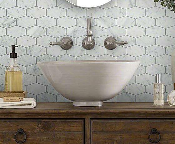 Bathroom sink handles mounted on beveled marble tile, basin below on wood counter