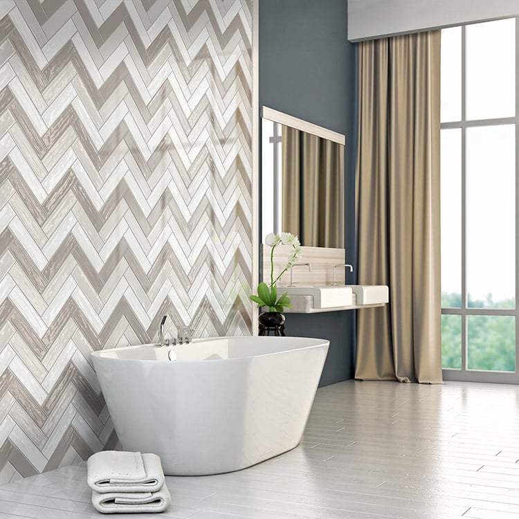 Greige, pearl, and white glossy wall tile in a herringbone set on a wall in a light modern bathroom